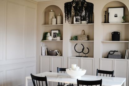 A dining room with arched built-in shelving painted cream