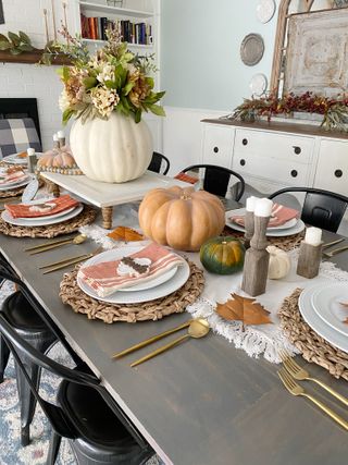Thanksgiving table with gourds and golden accents on table setting