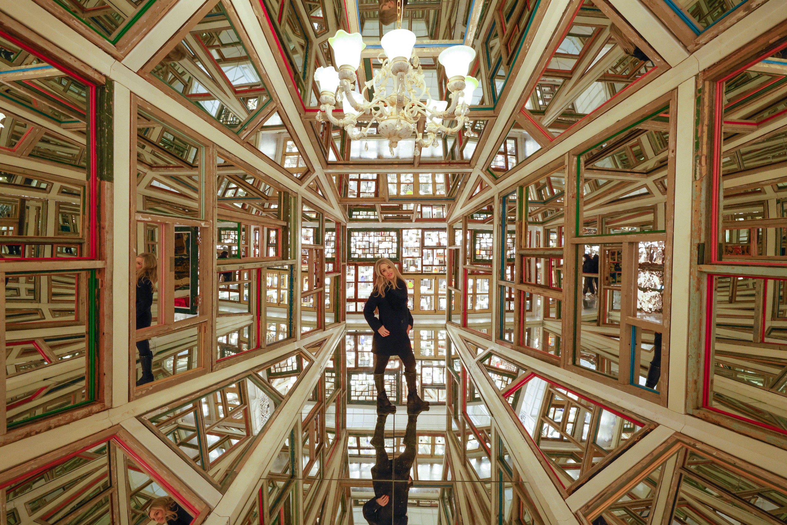 A woman stands in a room that is mostly mirror