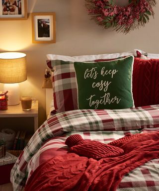 Traditional country Christmas-themed bedroom with check bedding and green cushion with slogan