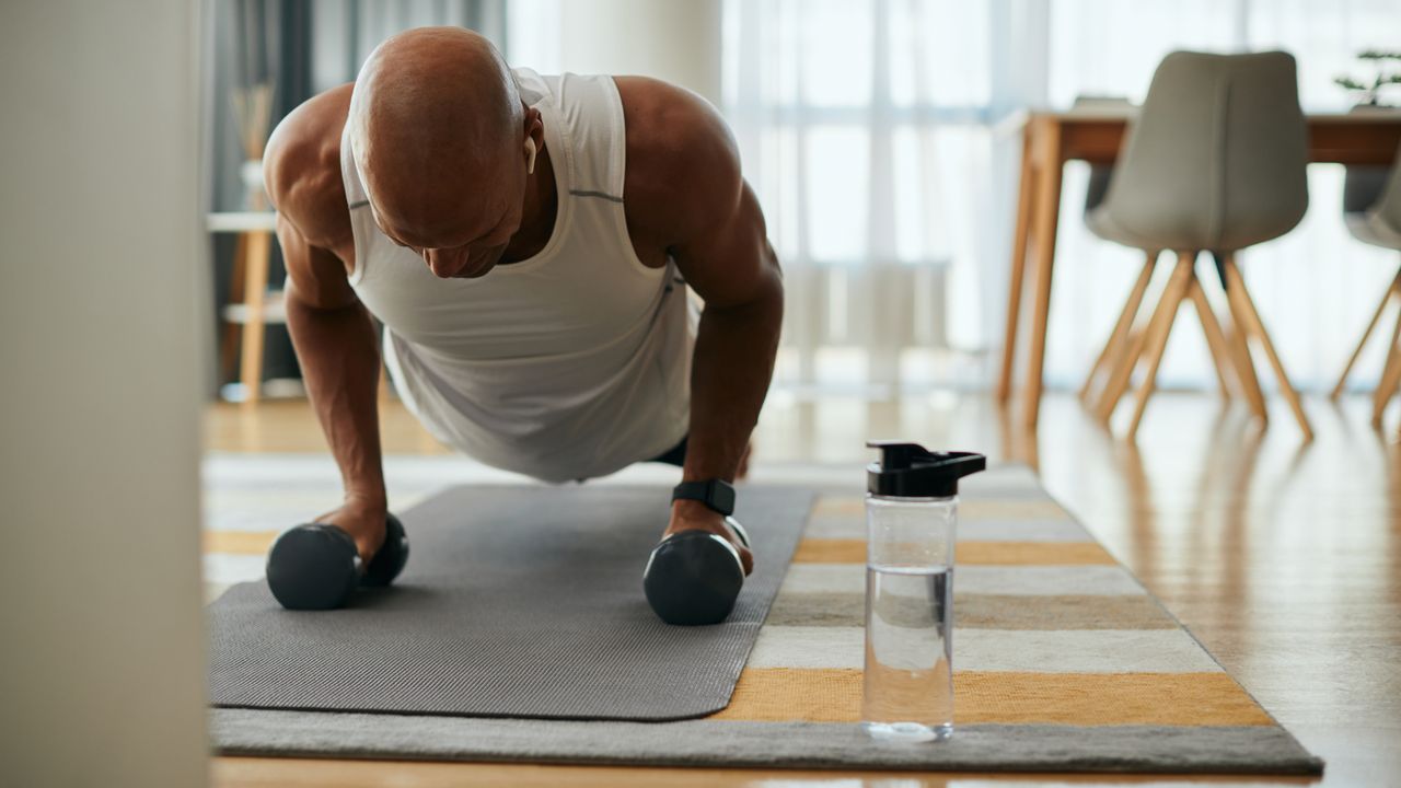 Man performing dumbbell exercises at home