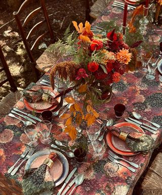 Decorated fall table with patterned tablecloth, flowers and foliage, tableware