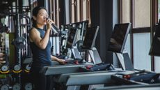 Woman drinking from a water bottle after a treadmill session