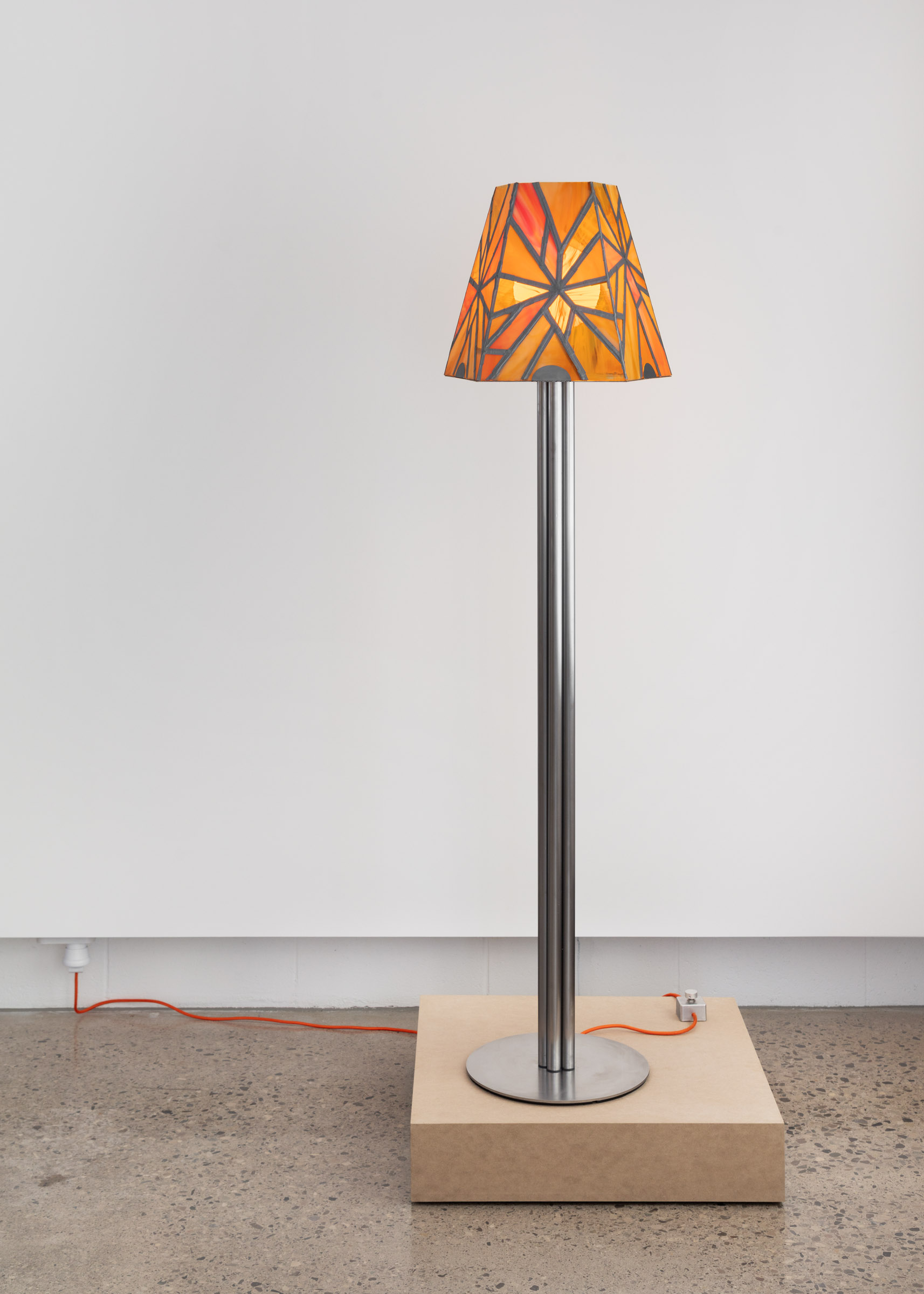 Stained glass lamp standing on a plinth in a gallery space