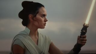 Still from a Star Wars movie. Here we see Rey Skywalker wearing white robes and holding a lightsaber.
