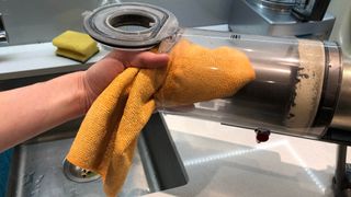 The Dyson V11 canister being cleaned with a damp microfiber cloth