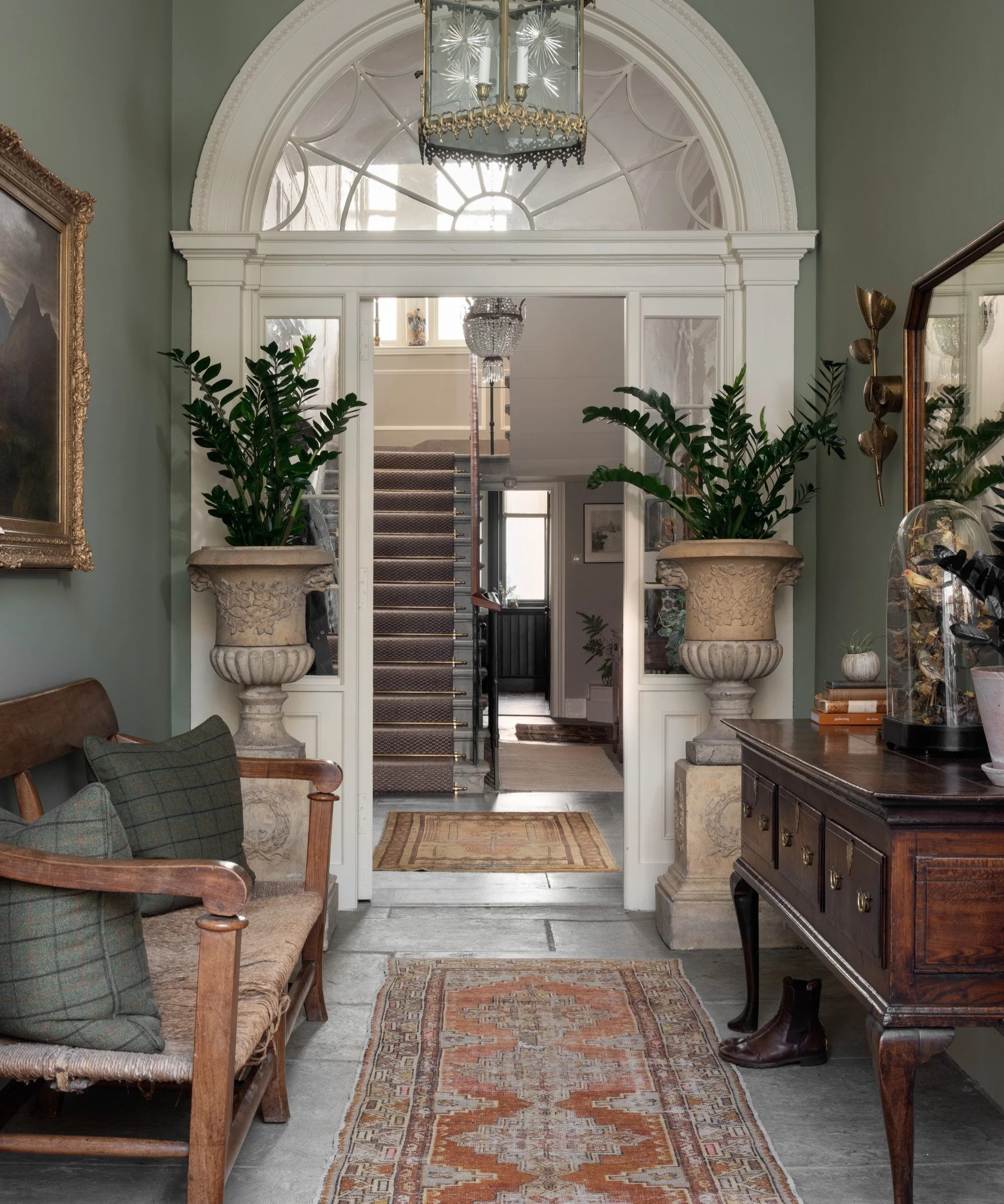 an entryway with a vintage table and bench on either side and a persian runner rug on the floor