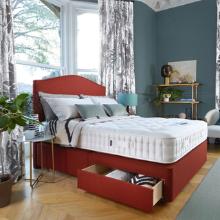 A red divan storage bed in a bedroom with the storage drawer open