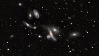a swarm of galaxies varying in size paints a scattering across black space.