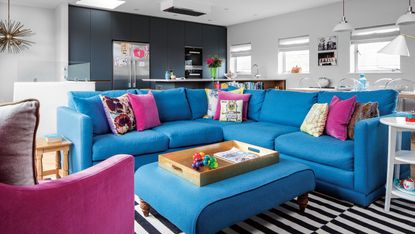 Open plan kitchen living room with blue L-shaped sofa and ottoman