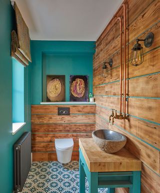 Blue and wood paneled bathroom with blue patterned floor tiles and stone basin