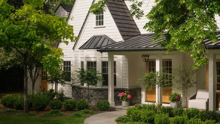 the exterior of a sweet white clad home in Cherry Hills, Colorado, surrounded by greenery and plants
