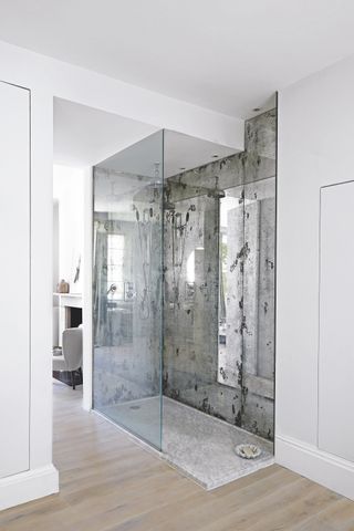 walk in shower with wooden flooring, mirrored glass walls, glass shower door, open plan