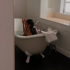 Woman sitting in bathtub. 
