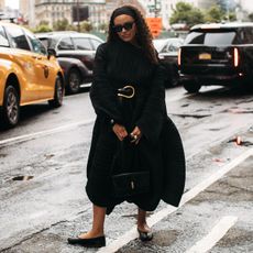 woman wearing black dress, sweater, and a black belt 