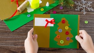 child making a chistmas tree card using buttons as baubles