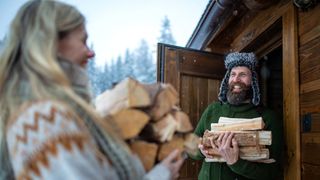 how to season wood: couple carrying firewood