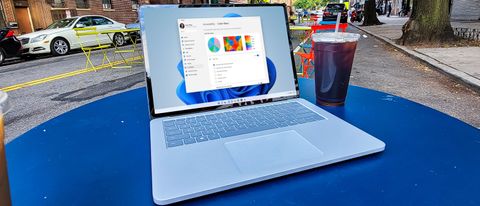 Surface Laptop Studio on a blue table, next to a cup of coffee, on a street in New York 