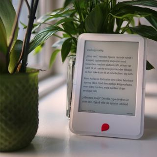 En Mofibo e-bogslæser står lænet op ad en grøn potteplante