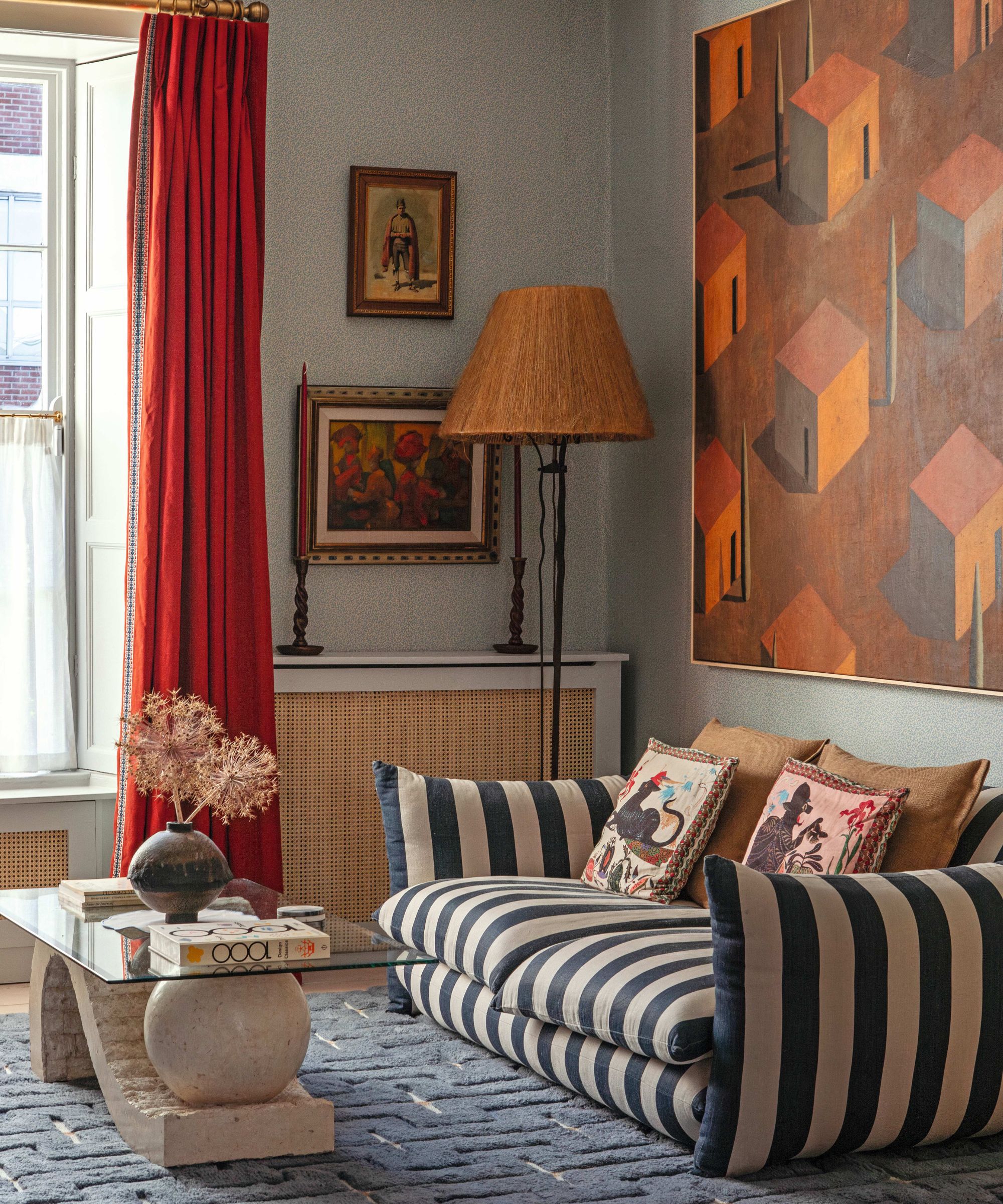 a playful light blue living room with red curtains and a bold white and navy striped couch