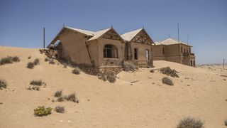 A photo from Kolmanskop, Namibia showing an abandoned home half swallowed by sand.