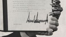 Photo collage of a signed executive order being held up by Trump's hand, as well as a robot hand
