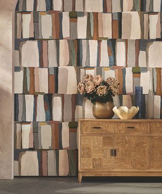 patterned wallpaper with patchwork pattern and sideboard with vase of flowers and bowl