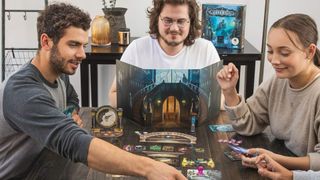 Players sat around a table playing Mysterium, with cards and tokens strewn across the surface