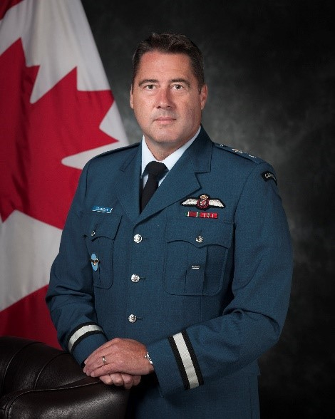 a man stands in a military uniform in front of a canadian flag.