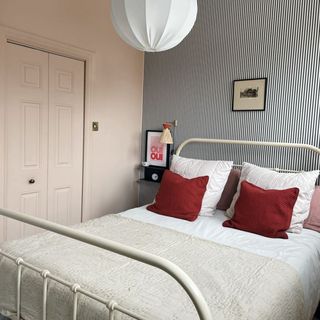 Bed inside bedroom with pinstripe feature wall and art prints