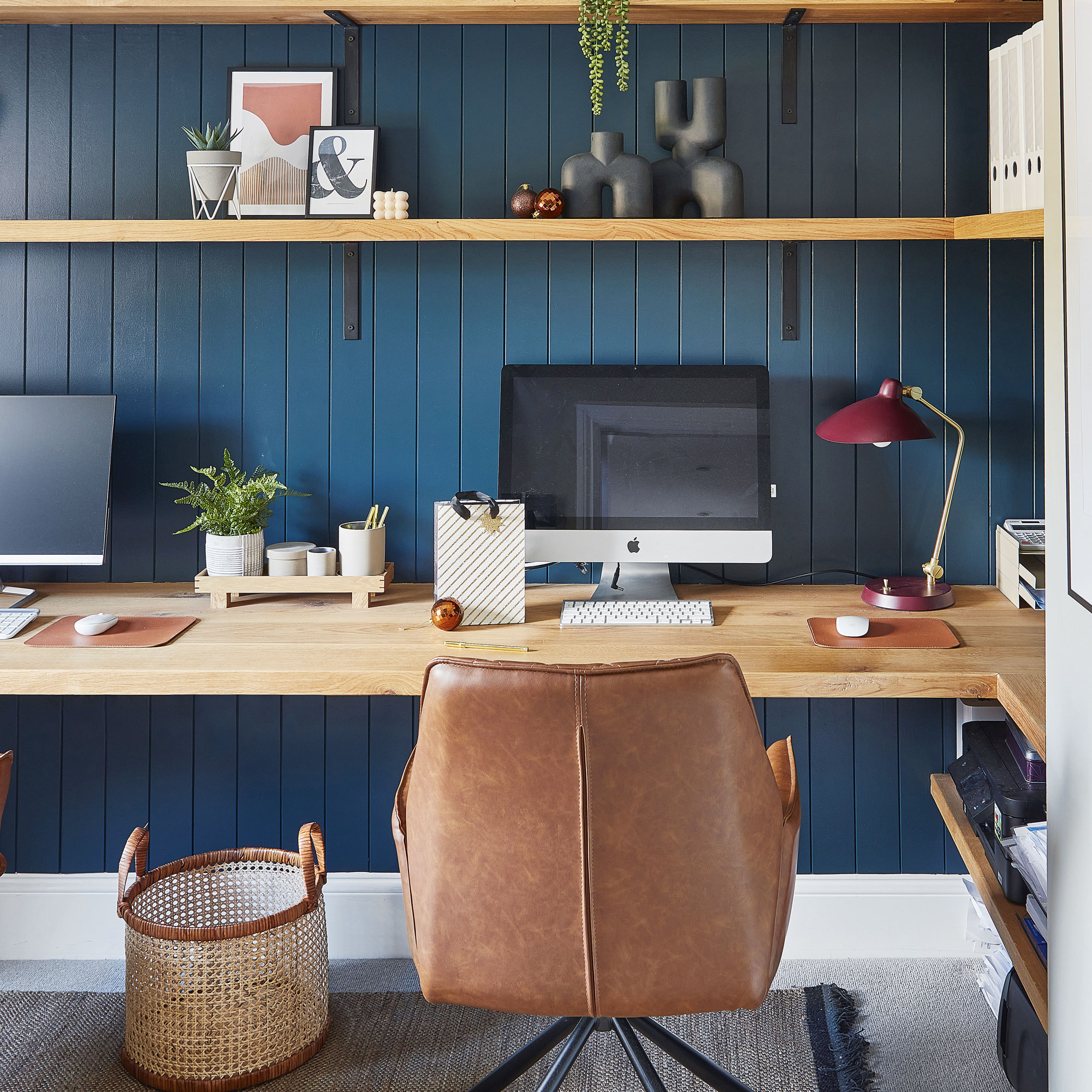 Blue home office with wooden shelves and leather desk chair
