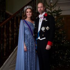 Kate Middleton wearing a blue gown and Prince William in a suit in front of a Christmas tree