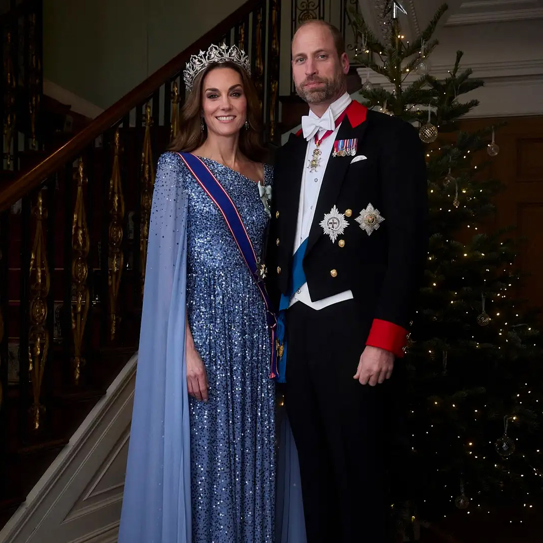 Kate Middleton wearing a blue gown and Prince William in a suit in front of a Christmas tree