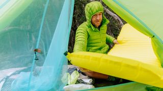 how to choose a sleeping pad: man putting pad in tent