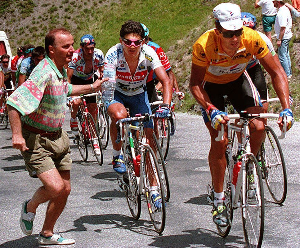 ISOLA 2000 FRANCE An unidentified Tour de France fan runs with a bottle of water beside Italian rider Claudio Chiappucci C and Spaniard Miguel Indurain 15 July 1993 during the highest climb of the Tour the 2802meterhigh pass of La Bonette during the 11th stage Swiss Tony Rominger won the stage from SirreChevalier to Isola 2000 Photo credit should read PASCAL PAVANIAFP via Getty Images