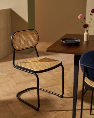 A dining chair with cane seat and backrest and black metal frame