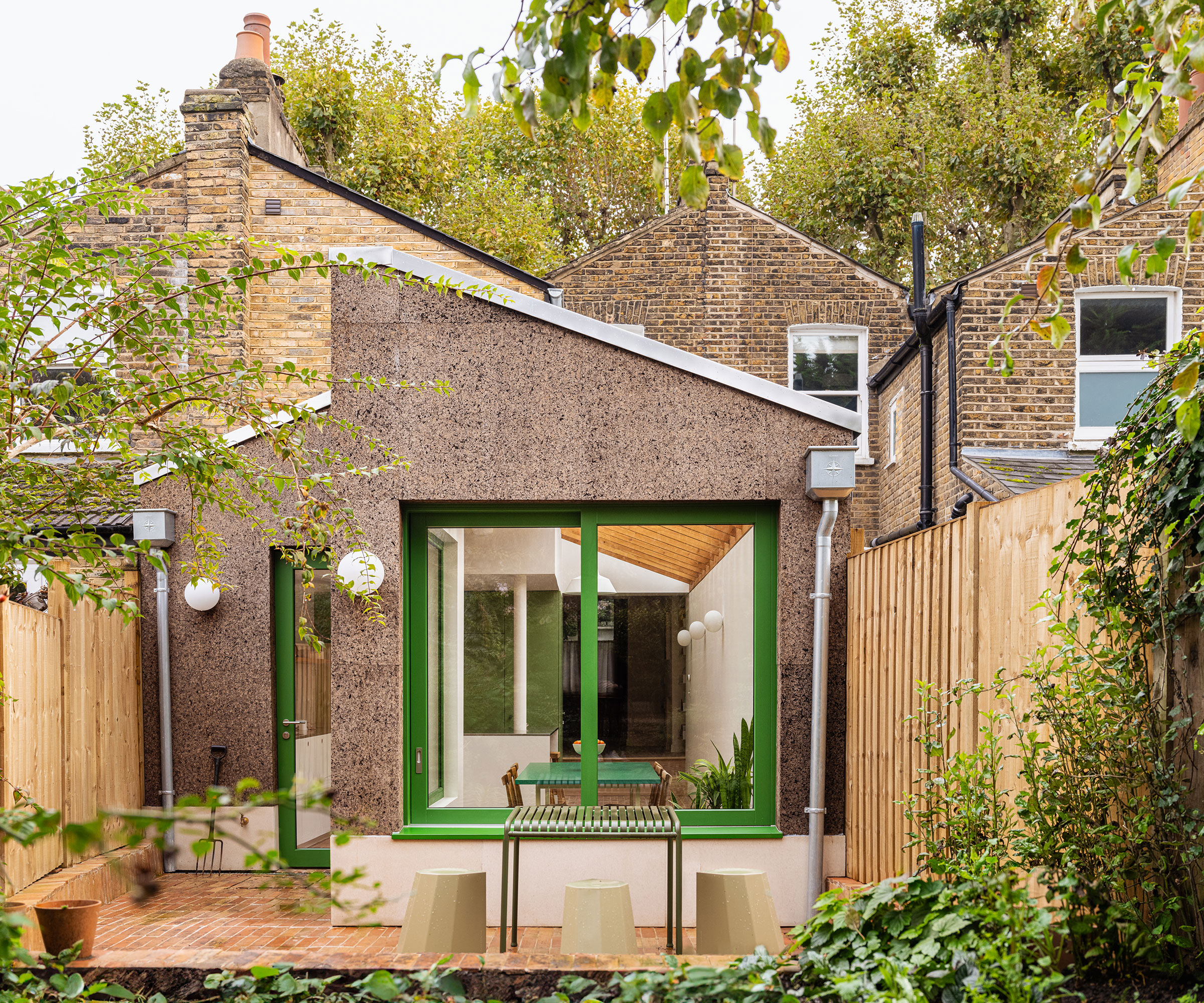 cork cladding on terraced house extension with green windows and doors