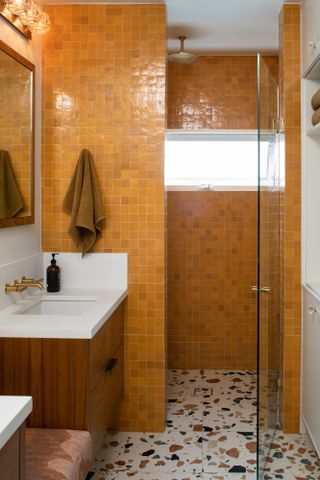Deep yellow tiled bathroom with terrazzo floor