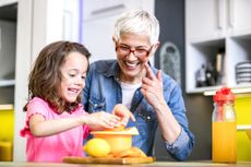 Grandmother and granddaughter in the kitchen making lemonade and talking at the counter.