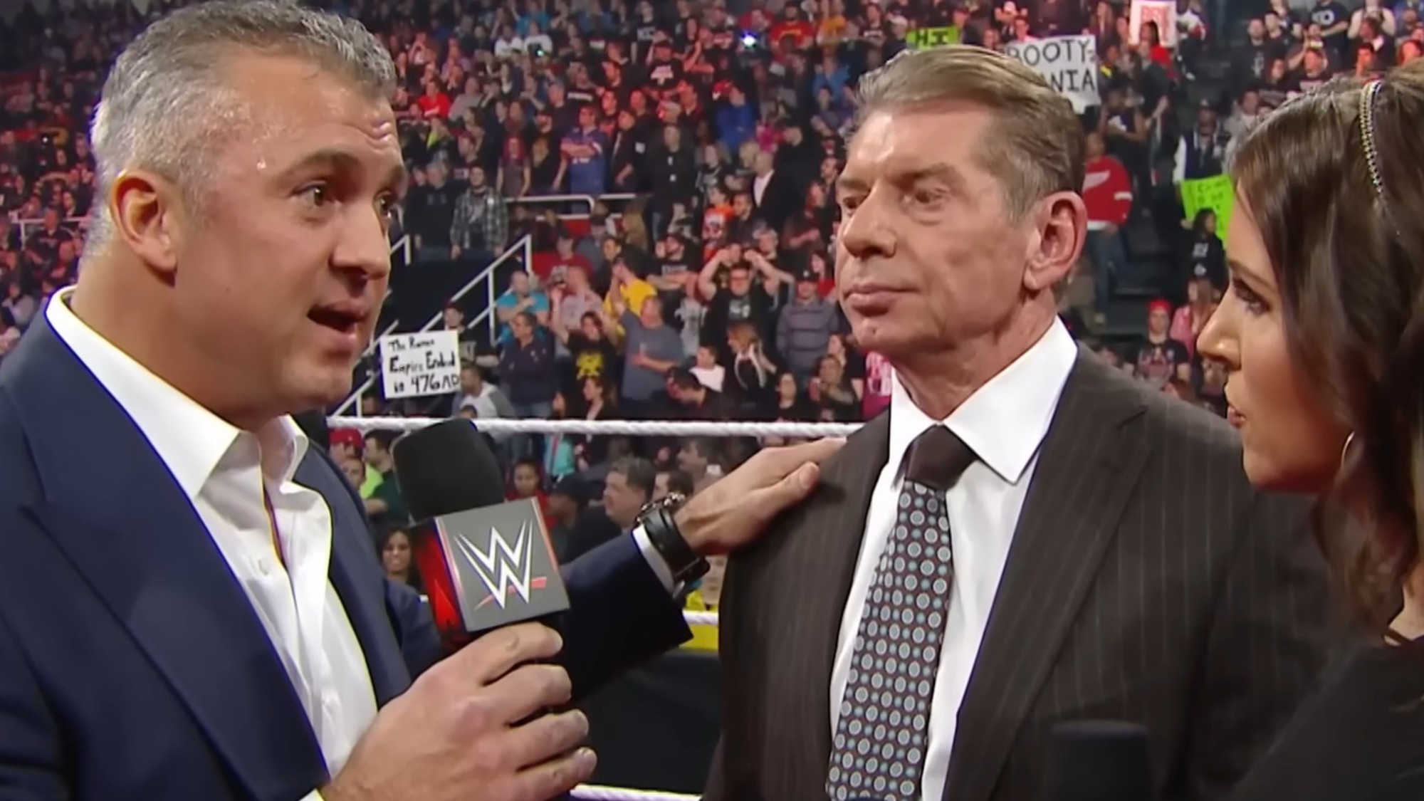 Shane McMahon with his hand on his dad's shoulder