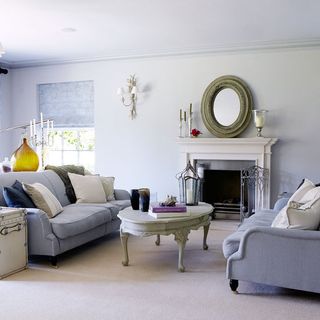 living area with white wall and fire place and blue sofa with coffee table