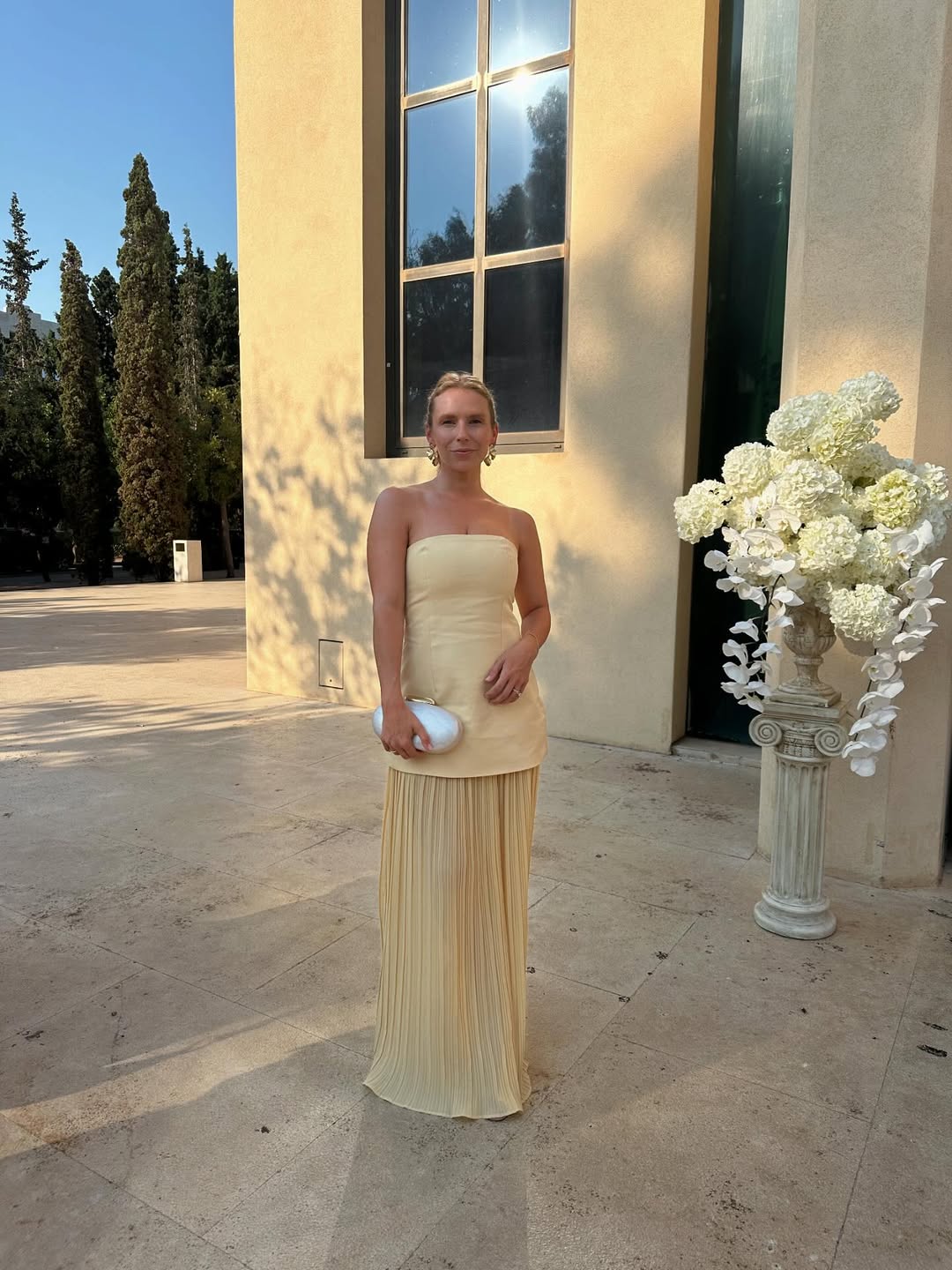 Influencer Amanda Sorensonn wearing a strapless yellow dress and pebble clutch bag.