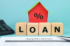 Building blocks spell out loan in front of a tiny house model.