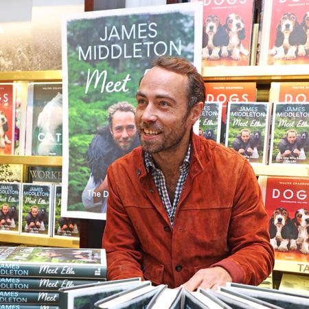 James Middleton sitting in front of a table of his memoir and bookshelves with dog books