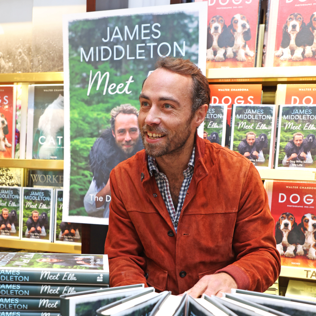 James Middleton sitting in front of a table of his memoir and bookshelves with dog books