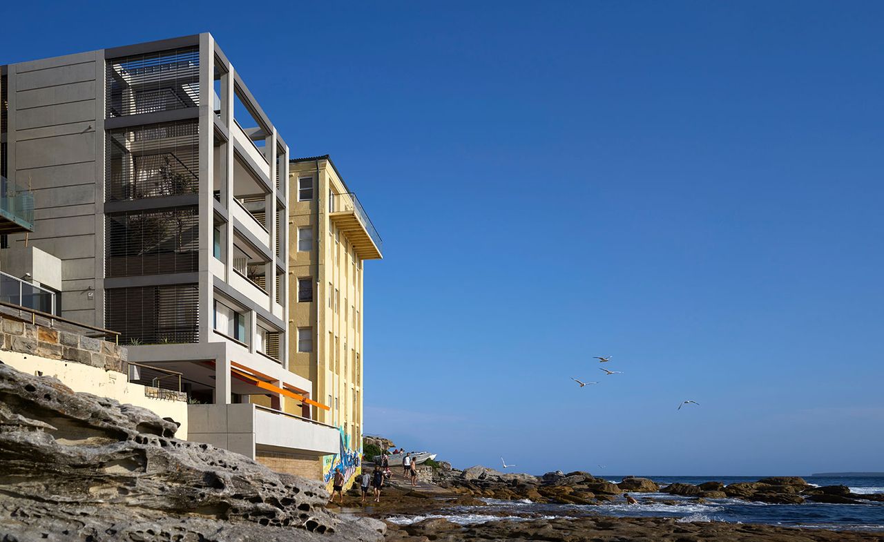 exterior view of a residential shoreside concrete clad home on the rocky shores of bondi beach