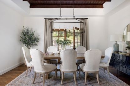 dining room white upholstered chairs and black credenza beamed ceiling neutral colors french window open wooden and dining table with white walls
