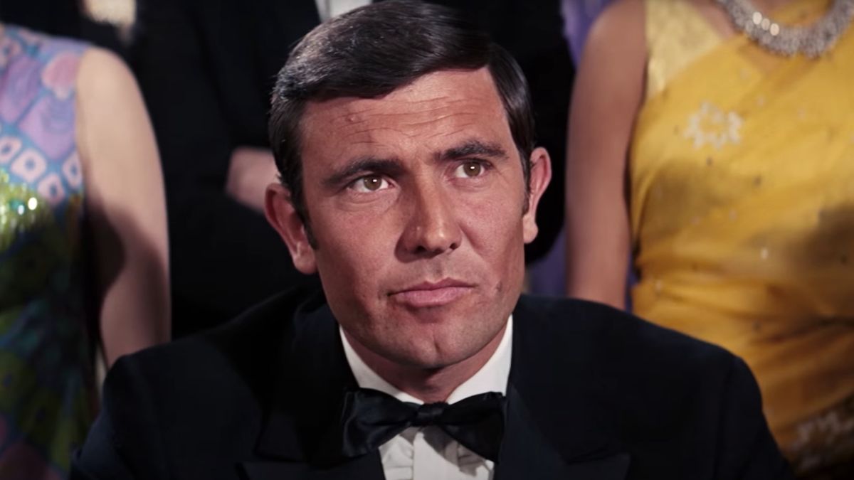 George Lazenby sits at the card table in a tuxedo in On Her Majesty&#039;s Secret Service.