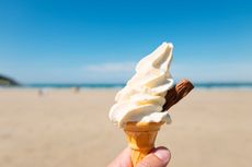 A close-up of a 99 ice cream against a beach backdrop