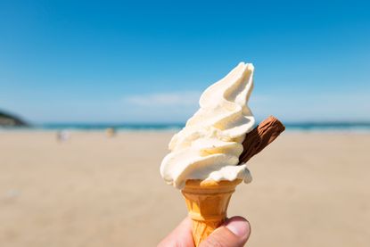 A close-up of a 99 ice cream against a beach backdrop